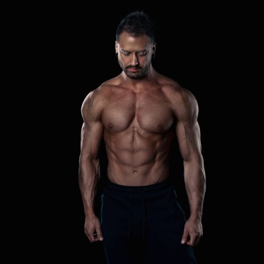 Acımasız güçlü vücut geliştirmeci atletik erkek siyah arka plan üzerine poz.