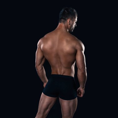 Acımasız güçlü vücut geliştirmeci atletik erkek siyah arka plan üzerine poz.
