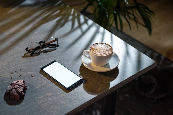 Zbliżenie na filiżankę kawy, ciasteczka owsiane, okulary i zdejmowany telefon rezygnować pusty ekran. — Zdjęcie stockowe