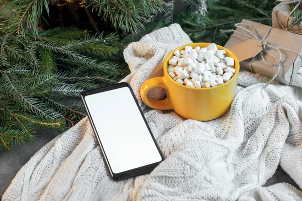 Fincan kakao Marshmallows ile ve hareket eden telefon ile Noel ağacı ve kazak arka plan boş ekran.