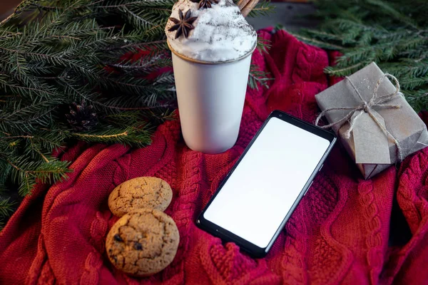 Kahve Kupası, yulaf kurabiye ve Noel ağacı ve kazak arka plan üstünde hareket eden telefon