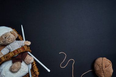 İplik örgü, oyuncak ve örgü iğneleri sepet koyu arka plan üzerinde ayı.
