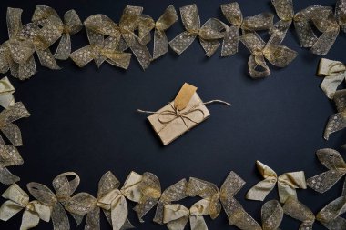 Hediye kutusu ve altın hediye yay koyu arka plan üzerinde düz lay.