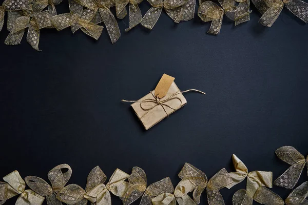 Colocación plana de caja de regalo y arcos de regalo de oro sobre fondo oscuro . —  Fotos de Stock