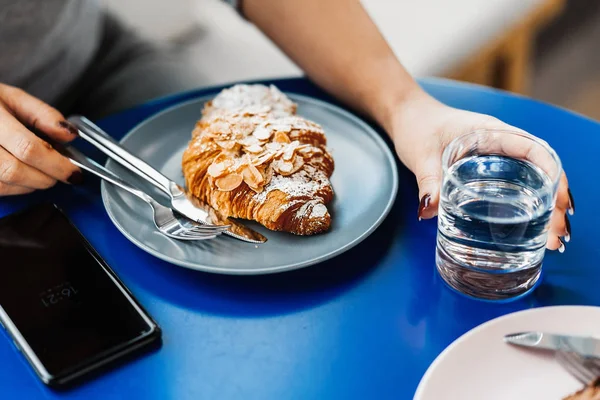 Bir fincan kahve, kruvasan ve cep telefonu ile tablo tutan kadın kapatmak.