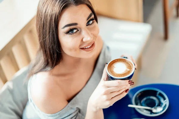 Primer plano de la mujer mirando a la cámara, sosteniendo la taza de café . — Foto de Stock