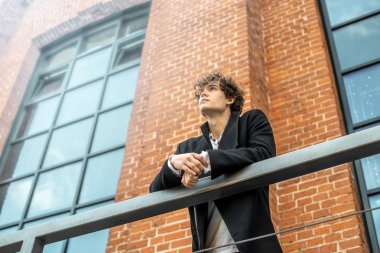 Çekici dalgın adam kırmızı tuğla bina arka plan üzerinde merdiven üzerinde ayakta.