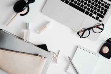 Kozmetik, parfüm, Gözlük, debriyaj çanta, laptop ve Not defteri düz lay.
