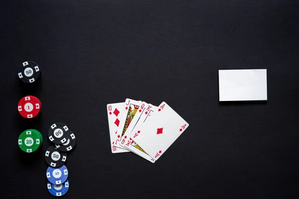 Casino chips, playing cards and business card on minimalistic black background . Casino game. Online casino. Gambling concept, poker mobile app. Poker game theme. Royal flash.