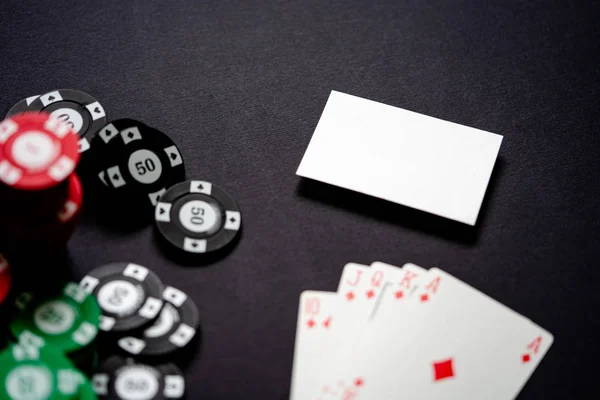Casino chips, playing cards and business card on minimalistic black background . Casino game. Online casino. Gambling concept, poker mobile app. Poker game theme. Royal flash.