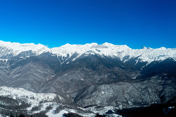 Views of beautiful snowy mountain and blue clear sky in ski resort.