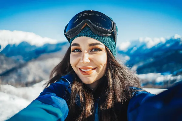 Gülümseyen ve selfie dağ arka plan üzerinde yapım çekici snowboard kız.