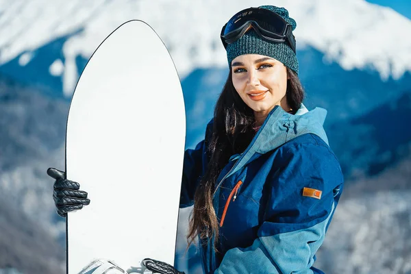 Gülümseyen ve dağ ve yamaç arka plan üzerinde poz snowboard kızın yakın çekim.