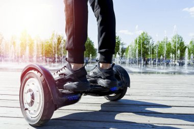 Man riding hoverboard in the park. Close Up of Dual Wheel Self Balancing Electric Skateboard. electrical scooter outdoors. Gyroscooter. clipart
