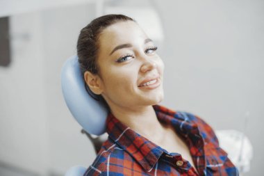 Gülümseyen ve stomatologist diş ofisinde beklerken kameraya bakarak istemcisinin yakın çekim.