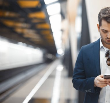 Genç çekici işadamı manifatura mesaj içinde hareket eden telefon için metro tren beklerken. Girişimci sorunları çalışma sürecinde yerleşti. Lating çalışma.