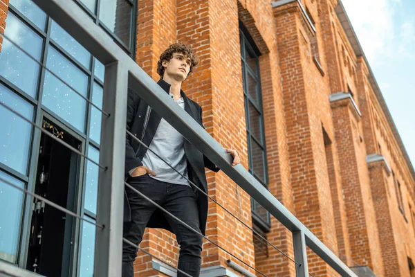 Atrakcyjne zamyślony człowiek stojący na schody na tle czerwony budynek bricked. — Zdjęcie stockowe
