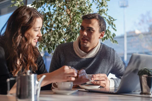 Young man and woman working in front of the laptop and drinking tea.