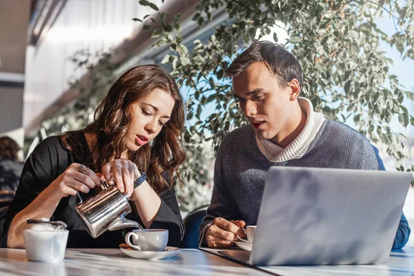 Joven hombre y mujer que trabajan delante de la computadora portátil y beber té . — Foto de Stock