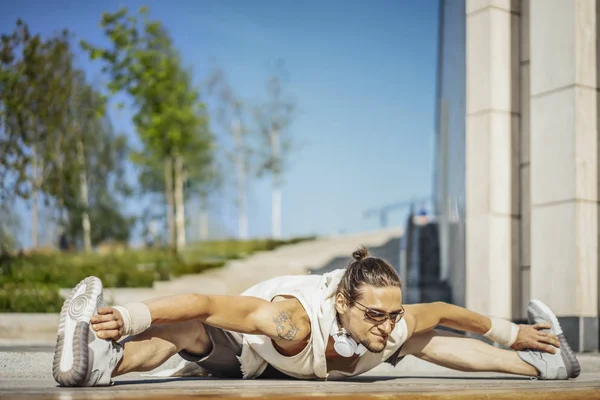 Atractivo atleta practicando yoga con mazas al aire libre en un parque moderno . — Foto de Stock