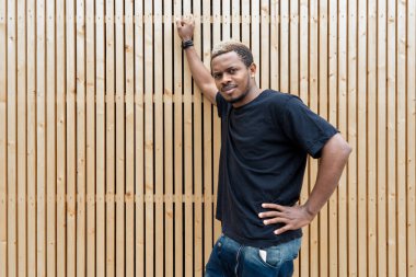 Ahşap arka plan üzerinde siyah T-shirt çekici esmer adamın yakın çekim.