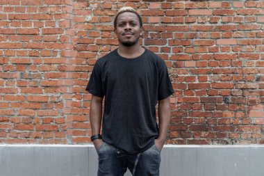 Genç çekici esmer adam kırmızı tuğla zemin üzerine siyah T-shirt.