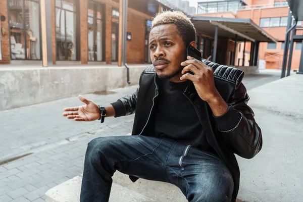 Hombre de piel oscura desagradablemente sorprendido y molesto hablando por teléfono móvil . —  Fotos de Stock