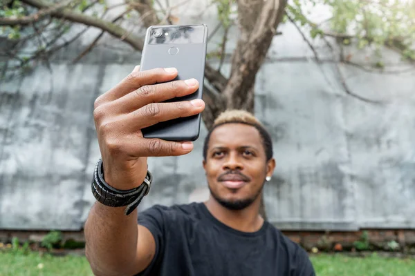 Primer plano del hombre de piel oscura en camiseta negra haciendo selfie en el teléfono móvil . — Foto de Stock