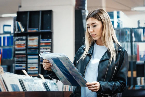 Mladá atraktivní žena vybírá vinylový desku v obchodě s hudebními nahrávkami. — Stock fotografie