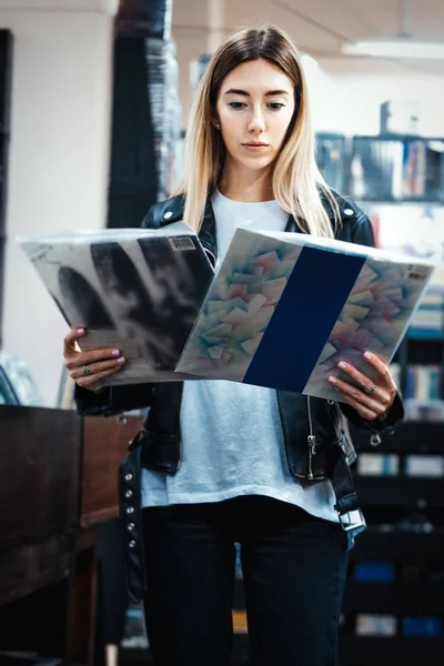 Mladá atraktivní žena vybírá vinylový desku v obchodě s hudebními nahrávkami. — Stock fotografie