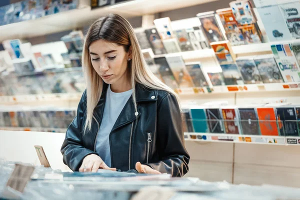 若い魅力的な女性音楽レコード店でレコードレコードを選択. ストック画像