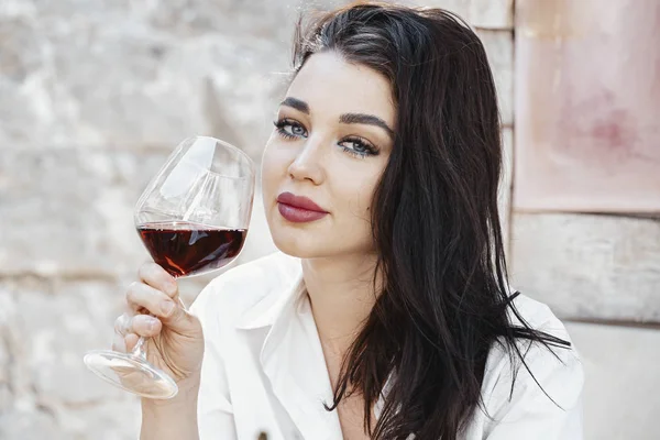 Молодая красивая женщина пьет красное вино в уличном кафе в европейском городе. — стоковое фото