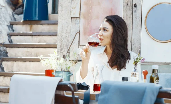 Mujer hermosa joven bebiendo vino tinto en la cafetería de la calle en la ciudad europea. — Foto de Stock