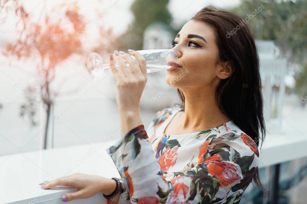 Young beautiful woman drinking champagne at the beach in street cafe.