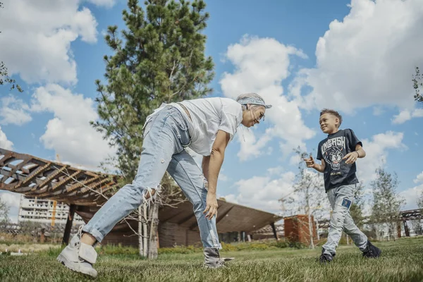 Giovane mamma divertirsi con i suoi figli al parco verde moderno. Concetto famiglia felice . — Foto Stock