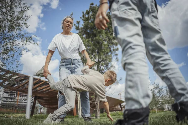 La giovane mamma si gira, girando con i figli al parco. Concetto famiglia felice . — Foto Stock