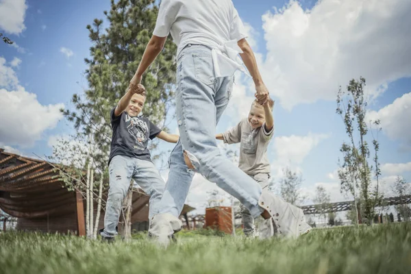 Mamá dando la vuelta, girando y divirtiéndose con sus hijos. Concepto de familia feliz . —  Fotos de Stock