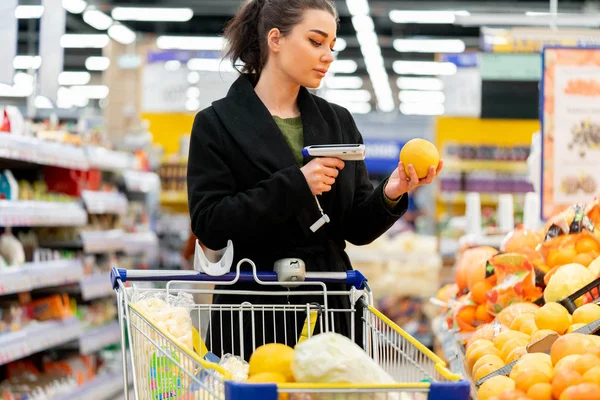 Woman holding bar code scanner and scanning products in store.