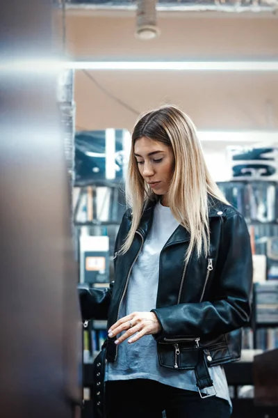 Young attractive woman choosing vinyl record in music record shop.