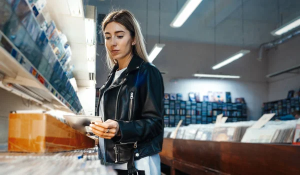 年轻迷人的女子在音乐唱片店选择了乙烯唱片. — 图库照片