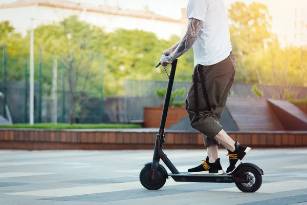 Primer plano del hombre montando scooter eléctrico negro en el hermoso paisaje del parque —  Fotos de Stock