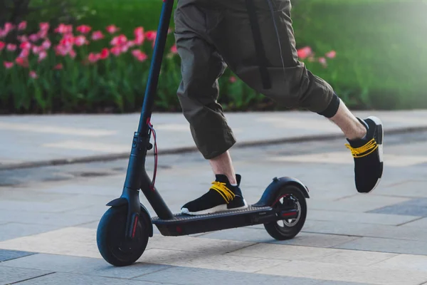 Primer plano del hombre montando scooter eléctrico negro en el hermoso paisaje del parque —  Fotos de Stock