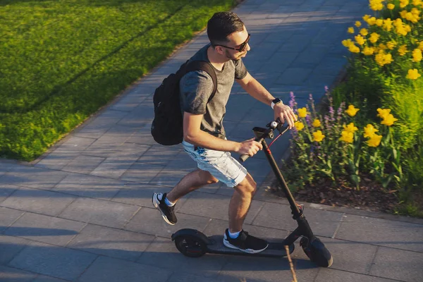 Homem montando scooter elétrico pontapé na bela paisagem do parque. Vista superior . — Fotografia de Stock