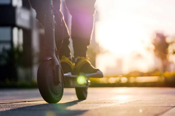 Gün batımında cityscape siyah elektrikli kick scooter sürme adam yakın