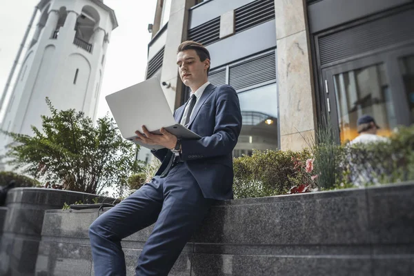 Biznesmen pracujący na laptopie obok centrum biznesowego w centrum miasta. — Zdjęcie stockowe