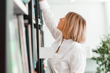 Genç çekici dalgın kadın bir kitap mağazası veya kütüphanede bir kitap için el çizim
