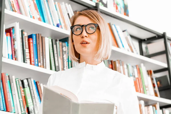 図書館で本を読むフォーマルな服を着た若い魅力的な女性. — ストック写真