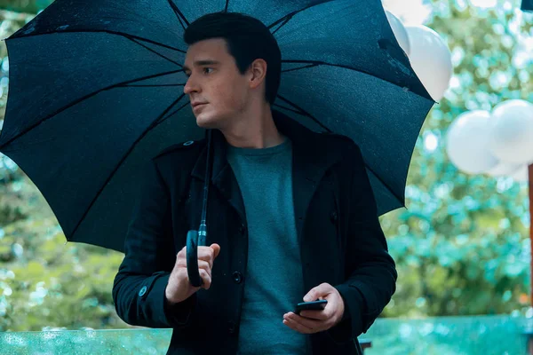 Jeune homme beau et cher avec parapluie le jour de pluie marchant dans le parc . — Photo