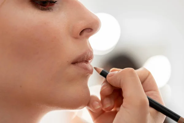 Make up artist applies lip pencil. Hand of make-up master, painting model lips — Stock Photo, Image