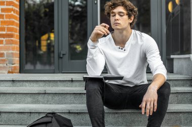 Modern adımlar bina ve Not Defteri'nde yapma oturan dalgın öğrenci.